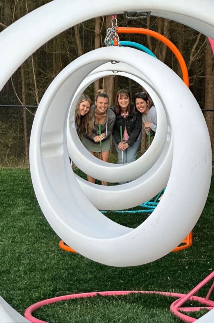 Friends playing mini golf through the spiral loop obstacle